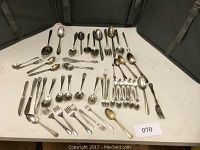 Full spread of over 50 pieces including various sizes of spoons, forks, knives, and serving utensils displayed on table