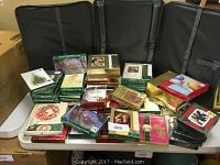 Multiple packs of Christmas cards arranged on table showing various designs and colors including green, gold, red, and white themed boxes.