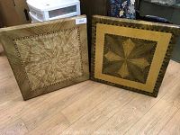 Two folding card tables leaning against a wall, showing their patterned wooden tops with distinct geometric designs.