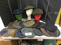 Front view of all caps arranged on table with three on bust forms