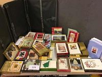 View of multiple packs of Christmas cards arranged on a surface with a black background. Includes unopened and opened sets featuring various holiday designs.