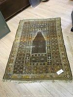 Full view of hand knotted earth toned rectangular rug laid flat on a floor showing overall pattern and condition.