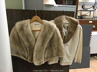 Front view of two vintage furs on hangers, showing mink fur stole and cashmere with fur collar.