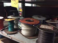 Multiple spools of assorted insulated wire on metal shelving