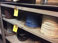 Shelf with three spools of assorted wire in brown, blue, and white colors