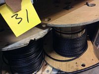 Four spools of assorted wired seen on metal shelving, includes black, green and white insulated electrical wiring.