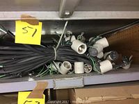 Multiple white ceramic/porcelain light sockets attached to black wiring bundled together on a shelf.