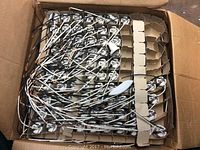 Box filled with multiple white and metal electrical sockets and switches packed in cardboard sectioned box.
