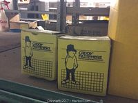 Two yellow boxes labeled Caddy Fasteners with construction worker logo placed on metal shelving.