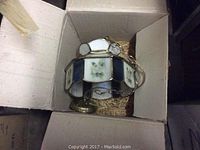 Ceiling fixture in a box showing stained glass panels with floral designs.