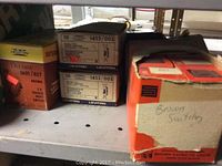 Photo showing several boxes on a metal shelf including Leviton and other branded boxes marked with 'Brown Switches'.
