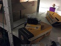 Black Hubbell electrical outlet device sitting on original Hubbell box on a metal shelf