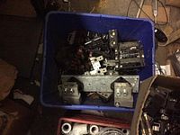 Blue container with various black fuse holders, fuse blocks, metal clips, and mounting brackets