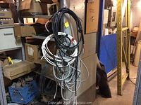 Loose flexible extension cords and cable wires hanging together, mixed colors and types visible.