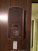 Front view of the musical chime unit mounted on wall with a vented grille and woodgrain finish.