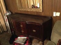 Front view of the vintage wooden buffet table with dark finish revealing its curved front and two drawers with brass handles.