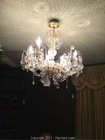 Full view of the chandelier mounted on the ceiling, showing the overall design with glass and crystal components and light bulbs.