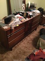 Wooden dresser with nine drawers visible, top cluttered with miscellaneous items, photographed from a side angle to show the drawer configuration, condition, and size.