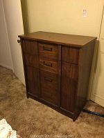 Front view of four-drawer wooden dresser showing missing handle on one drawer and wood grain finish.