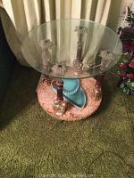 Photo showing the smaller round glass top end table with carved supports and pink marble-like lower tier base with lion paw feet.