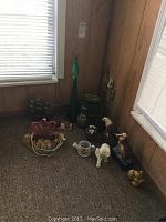 Wide view of assorted decorative items arranged on a carpeted floor corner, including glass bottles, figurines, and small containers