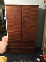 Front view of the wooden armoire with two paneled doors and two drawers at the bottom.