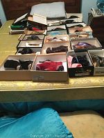 Various ladies heeled shoes displayed in boxes on a table in assorted colors and styles.