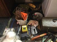 Photo showing a bucket with assorted hand tools, circular saw, box of nails, and a metal toolbox with tools around it