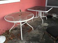 Both tables shown side by side against a pink wall on a concrete floor, with leaves and some dirt visible on the ground and furniture surfaces.