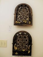 Pair of antique decorative metal vent grills mounted on wall with yellow silk flowers