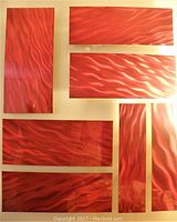 Close-up of six red metal panels with wavy textured 3D surface laid out on a flat surface.