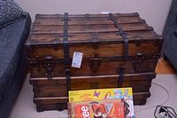 Front exterior view of closed trunk showing wooden slats, metal straps and central latch