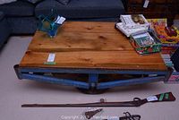 Full view of table showing cobalt blue metal base, wood plank top and cast iron wheel