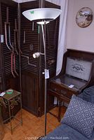 Full torchiere floor lamp with top frosted bowl-shaped shade and reading spotlight below, standing near furniture in room.