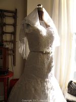 Full front view of lace wedding dress on mannequin with veil and brooch belt