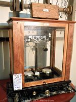 Full view of the scale inside its wooden and glass case sitting on a table