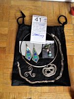 All sterling silver jewelry items arranged on black drawstring pouch showing necklaces, bracelets, pendants, and earrings.