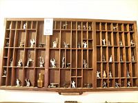 Full view of wooden tray mounted on wall with compartments and miniature figures