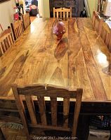 View of tabletop from one end with chair at end showing full planked surface and grain variation