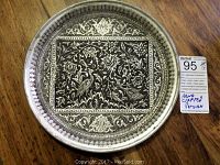 Front view of the round Persian plate showing detailed hand engraved floral and bird designs in the center with ornamental borders