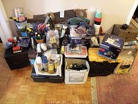 Full assortment of tools and household supplies arranged on floor and boxes, showing variety including cans, tape, hand tools, and power tool boxes