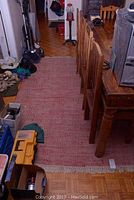 Red woven carpet under wooden dining chairs showing full length and color.