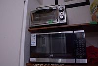Hamilton Beach toaster oven and Master Chef microwave oven stacked on wooden shelves.