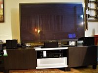 Full front view showing entire dark brown entertainment unit with TV and speakers on top
