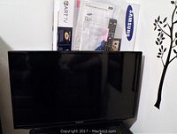 Samsung 32" TV displayed with box, remote control and manual behind screen
