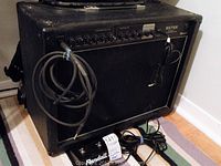 Front view of black Randall RX75R amplifier with attached instrument cable and footswitch on floor