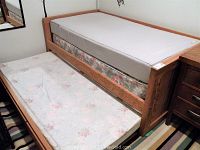 Full view of the twin trundle bed with mattresses visible on main bed and trundle section.