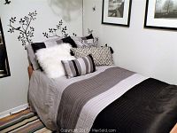 Bed dressed with black, white, and grey striped duvet cover and pillows arranged