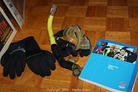 Photo showing black neoprene gloves, yellow snorkel, clear diving mask, and a PADI diver manual.