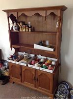 Front view of Vilas wooden display cabinet with small collectible items on shelves and cupboards closed